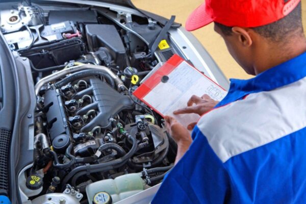 A man in a red hat inspecting a car engine. Importance of MOT Test in enhancing road safety.