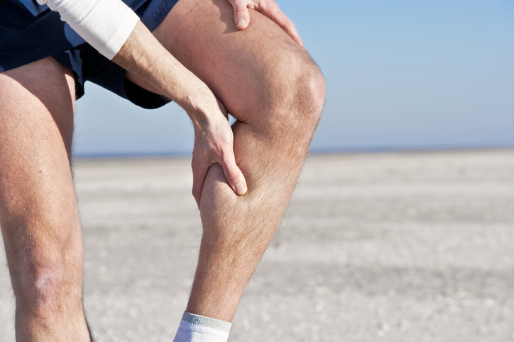 man suffering from a leg cramp massaging it with his hand